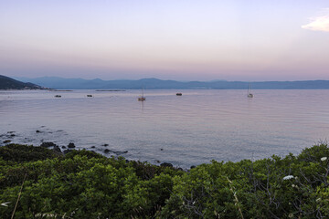 Fishing boats and yachts in the water of Ajaccio gulf under pinky sunset lights