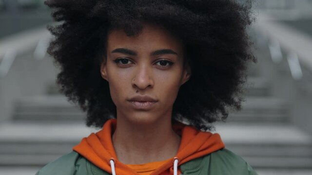 Close-up portrait of nice-looking multi-race beautiful elegant young woman with curly hair looking into camera with clam emotions. Fashion, beauty and female portraits concept.
