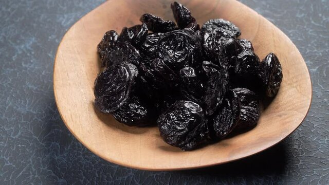 Pitted dried prune in wooden bowl rotation