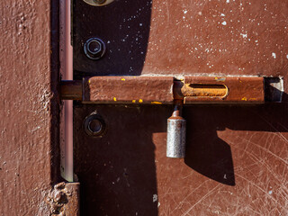 A closed iron latch on the brown metal door protects against outside intrusion. 