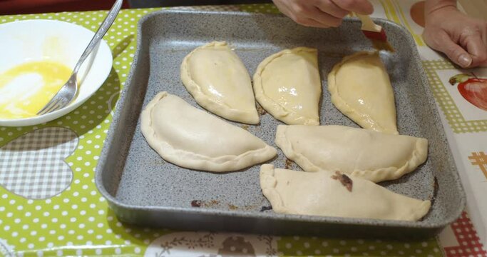Spreading the olive oil with the kitchen brush on the homemade panzerotti also called calzoni famous Italian street food