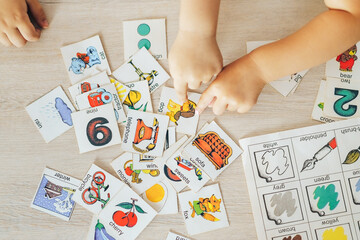 Children hands touching white cards of letters numbers and pictures for little kids on table. Time...