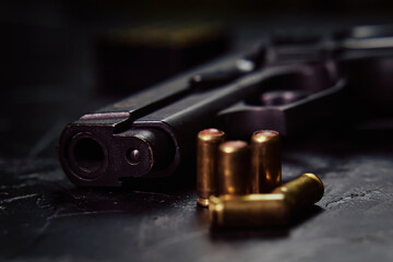 Firearms on concrete background. Close-up of gunpoint and bullets on table. Weapons and ammunition. Concept of crime and physical evidence. Pistol for defense or attack.