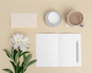 Flat lay office table desk. Workspace with blank copybook, pen, cup of coffee, white peony flower and fragrant candle as aromatherapy