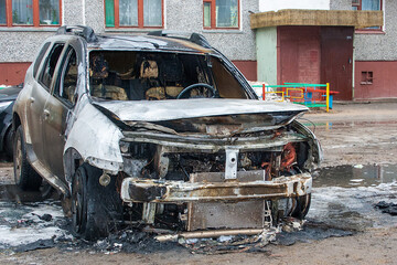 A burnt-out car in the yard. The aftermath of the fire. Set the car on fire