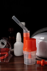 Inhaler mouthpiece on atomizing cup for compressor nebulizer on table against dark background. Medical equipment for inhalation therapy for asthma and respiratory diseases.