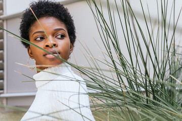 Trendy black woman near ornamental grass on street