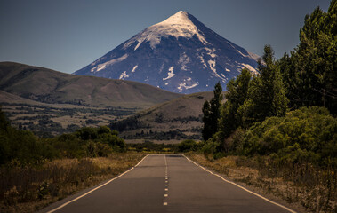 Fototapeta na wymiar Road in Patagonia Argentina. In the background the famous Volcán Lan´ín (Lanín Vulcano) that gives name to the Lanín National Park, one of the Argentina´s oldest and biggest. 
