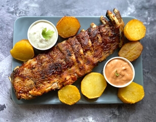 Grilled barbecue pork rib with fried potatoes, american sauce and garlic sauce. 