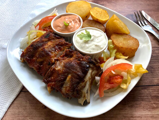 Grilled barbecue pork rib with fried potatoes, american sauce and garlic sauce. 