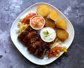 Grilled barbecue pork rib with fried potatoes, american sauce and garlic sauce. 