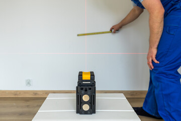 specialist mark the point and the level on the wall with an electronic laser