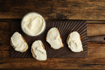 Fototapeta na wymiar Bread with cream cheese on wooden table, top view