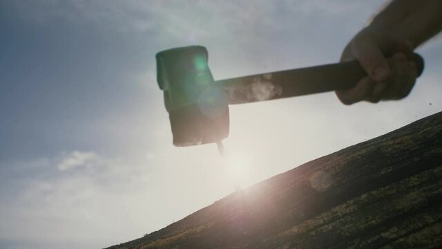 A hammer hitting a nail into an old piece of wood at sunset. Super slow motion footage