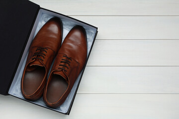 Pair of stylish leather shoes in black box on white wooden background, top view. Space for text - Powered by Adobe