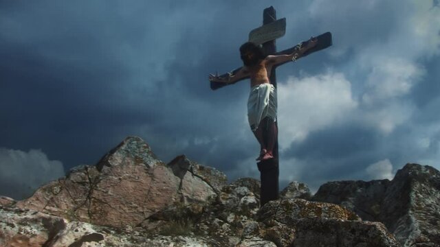 Jesus Christ hanging on Cross against cloudy sky.