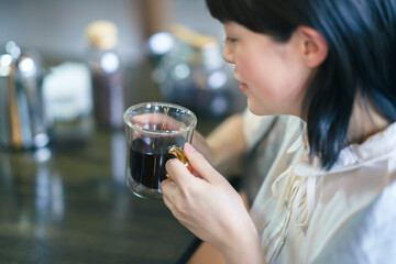 暖かい雰囲気の空間で、コーヒーを飲む若い女性