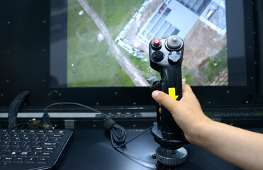 Operator hand holding a joystick control of the control panel station for an unmanned aerial vehicle, monitor © Yurii Zushchyk