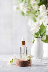 Jasmine essential oil in a glass dropper on a background of jasmine flowers.