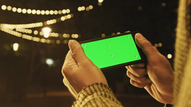 Handheld Camera: Point of View of man at Using Phone With Green Mock-up Screen Chroma Key Surfing Internet Watching Content Videos Blogs Tapping on Center Screen