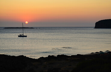 Sunset over the water with sailboat at anchor in Falasarna bay on the west coast of the Greek island of Crete