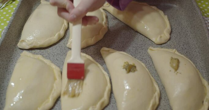 Spreading the olive oil with the kitchen brush on the homemade panzerotti also called calzoni famous Italian street food