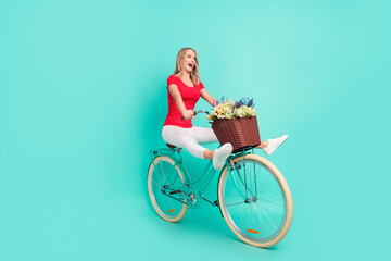 Full length body size photo woman riding crazy retro bicycle flower basket isolated vivid teal...