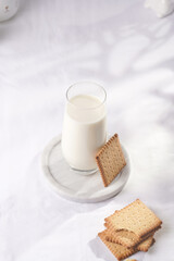 A glass of milk on a marble plate on a white table cloth and freshly baked cookies