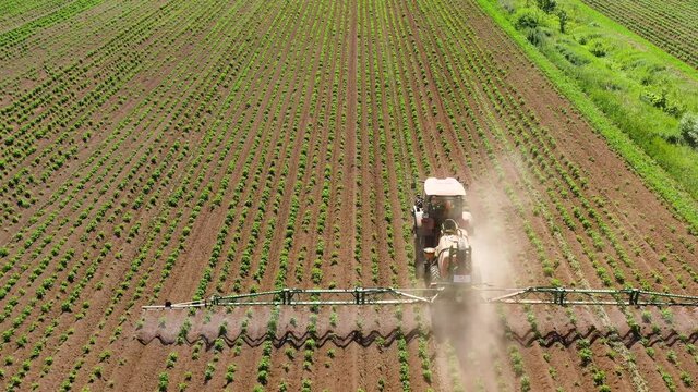 Tractor with pesticide fungicide insecticide sprayer on farm land, top view. Spraying with pesticides and herbicides crops.