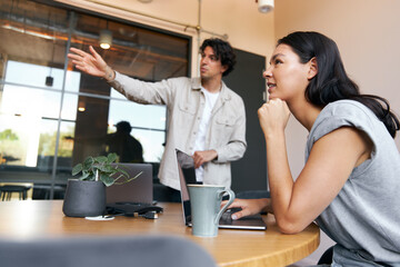 Young couple with laptops at desks preparing for online meeting in rented open plan office space