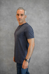 Obraz premium Side view portrait of handsome man standing against gray wall
