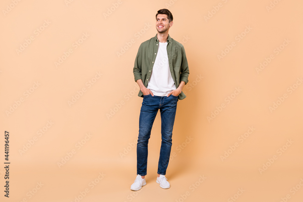 Poster full size photo of dreamy young man look empty space hold hands pockets jeans isolated on beige colo