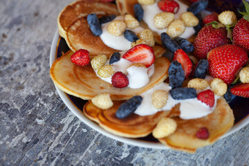 Pancakes on a plate with berries and cream