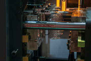 The plastic drinking bottles in the  blowing mold machine. The operation of PET bottle processing by blowing process with the blowing mold.