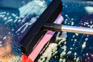 Closeup shot of washing the front window of a car with a mop in a self-service car wash station