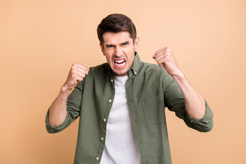 Photo of furious young angry man raise fists fighter argument bad mood isolated on pastel beige color background