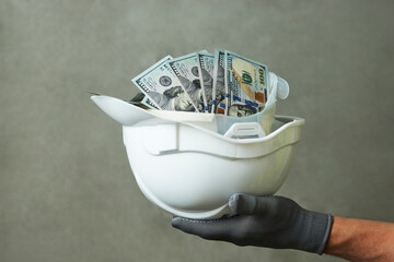 Construction worker with a hard hat full of dollar money