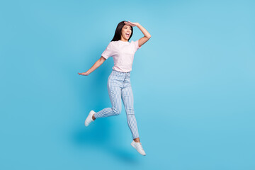 Full length body size view of attractive cheerful ecstatic thin girl jumping searching way isolated over bright blue color background