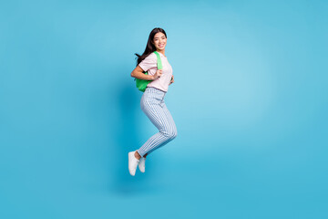 Full body profile side photo of happy nice young woman wear backpack smile jump isolated on blue color background