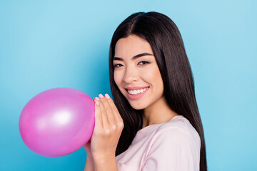 Profile side photo of young asian girl happy positive smile blow air balloon decoration isolated over blue color background