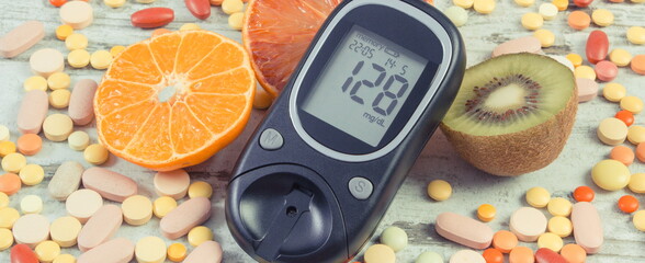 Glucometer with result of sugar level, fresh fruits and medical pills. Diabetes and healthy lifestyle and nutrition