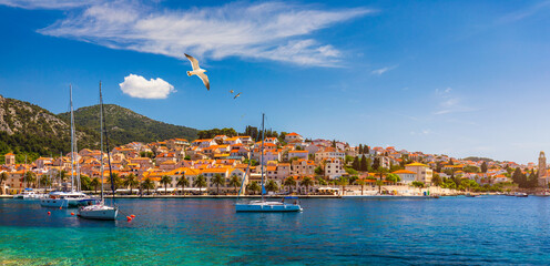 Hvar town with seagull's flying over city, famous luxury travel destination in Croatia. Boats on Hvar island, one of the many Islands near Dubrovnik and Korcula on the Dalmatian Coast of Croatia. - obrazy, fototapety, plakaty