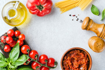 Obraz na płótnie Canvas Italian food ingredients dry pasta spaghetti, tomato sauce, basil frame flat lay with copy space. Cooking background