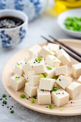 Tofu cut in cubes on a bamboo plate. Asian food