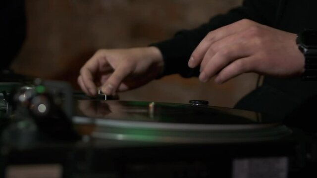 Hip hop dj plays music with retro turntable in slow motion video clip. Professional disc jockey playing musical tracks on vinyl record player in night club