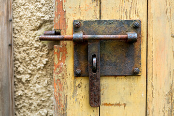 Old rusty door lock, visible paint peeling off and a concrete wall.