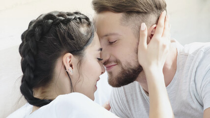 happy woman hugging bearded boyfriend with closed eyes at home.