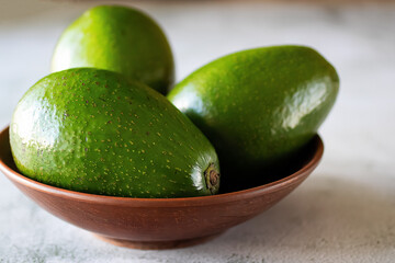 Ripe avocado in a brown plate on a light background.