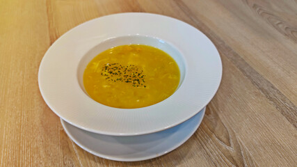 Delicious hot corn and egg soup in white bowl soup on wooden table.