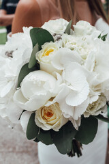 Wedding bouquet of white flowers in the hands of the bride